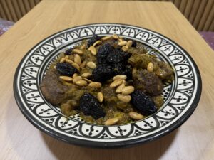 طبق اللحم بالبرقوق واللوز في صحن مغربي مزخرف من شهيوات أم قصي بطنجة