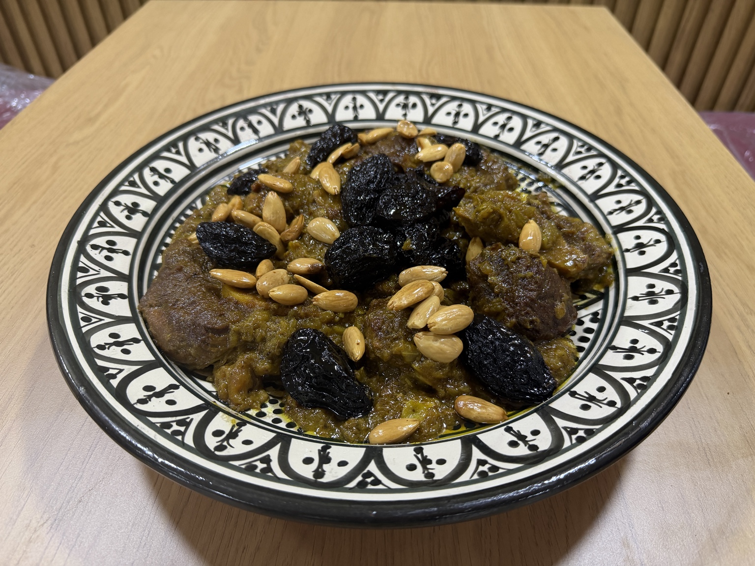 Moroccan meat with prunes and almonds on a patterned platter at Chhiwat Oum Koussay in Tangier